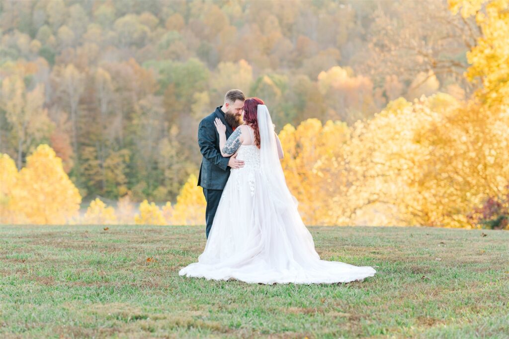 bride and groom standing in stunning fall foliage backdrop of a Lexington wedding in a field
